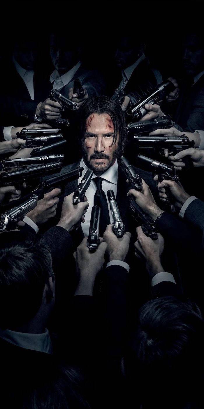 John Wick with many guns pointed at him